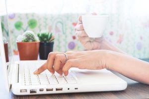 Rašymas skaitmeniniam pasauliui: svarbiausi principai, kurių negalima ignoruoti Asmuo rašo SEO optimizuotą straipsnį nešiojamame kompiuteryje, šalia užrašai ir kavos puodelis.