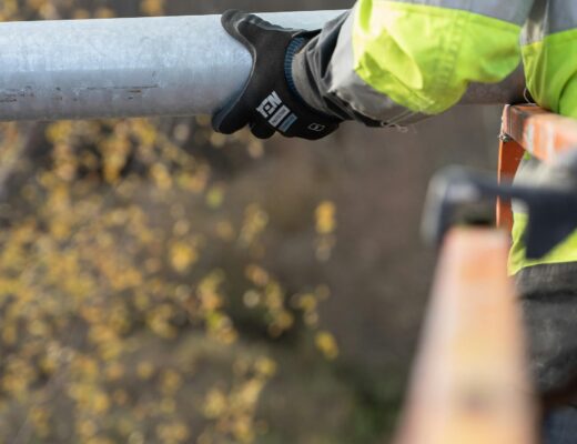 Specialistas kruopščiai tikrina apsauginių apraišų siūles ir tvirtinimo elementus prieš darbą aukštyje.